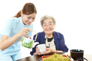 medical staff serving a tea to an old woman